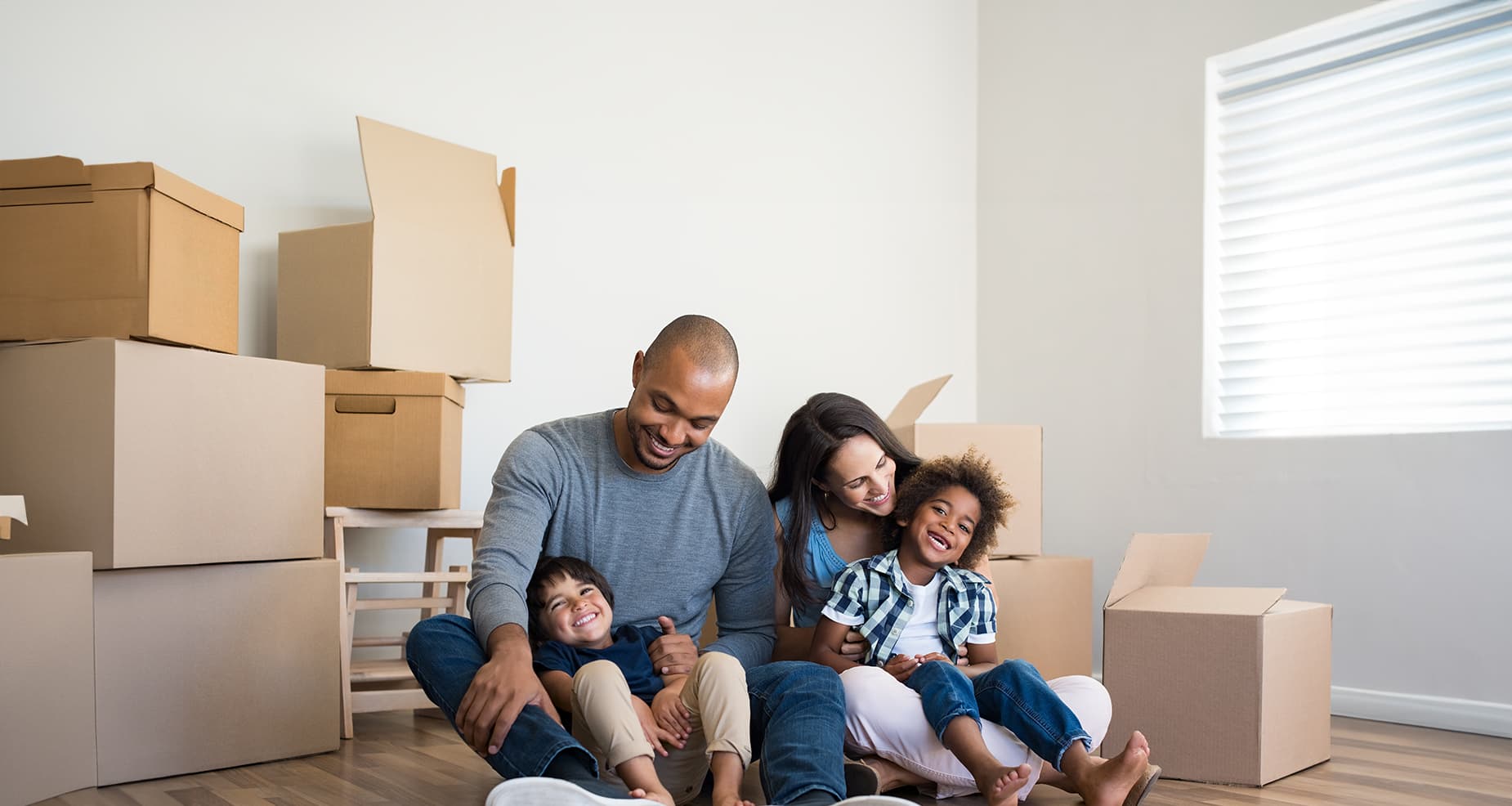 Happy family sitting on floor by moving boxes